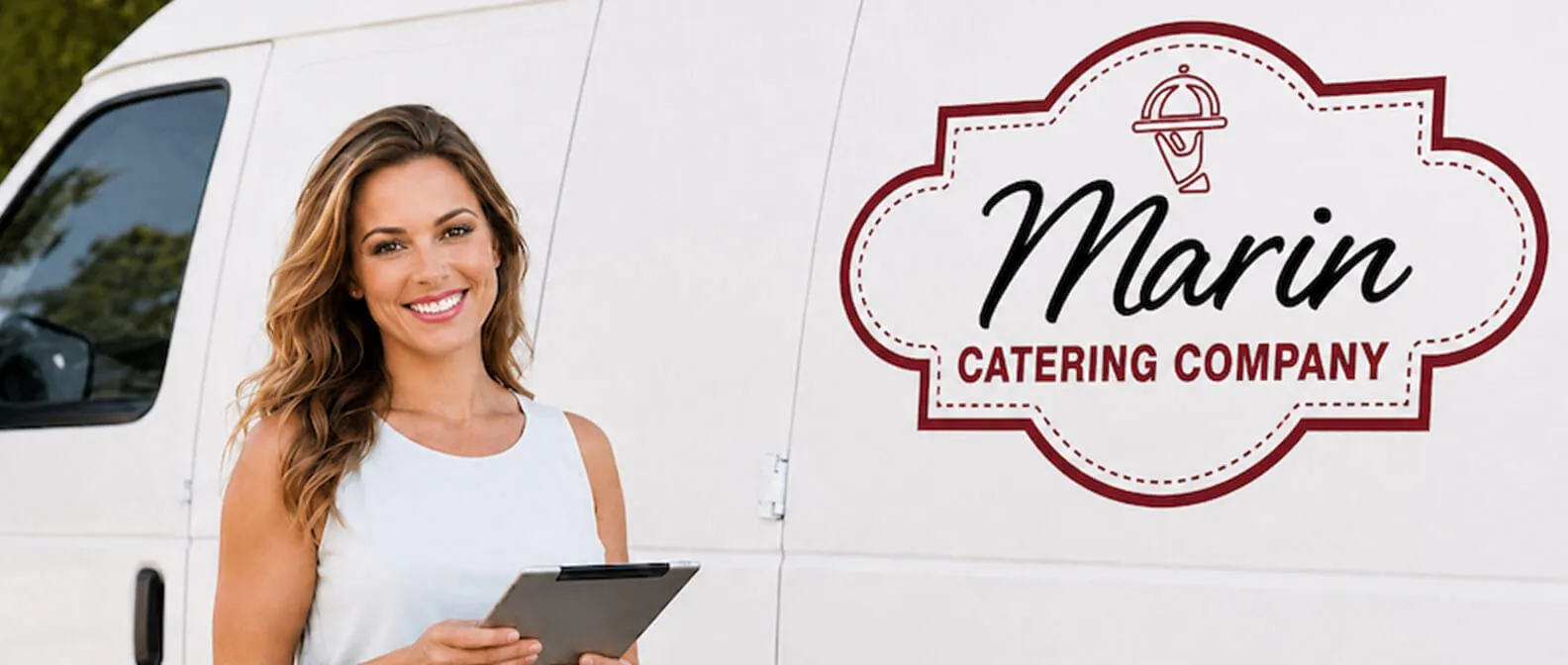 Marin Catering Company — catering coordinator reviewing the order sheet at the branded delivery van ahead of a drop-off in San Rafael, Novato, Mill Valley, and Sausalito Marin Catering Company event coordinator with a clipboard beside the branded white catering van before a drop-off catering delivery in Marin County, CA